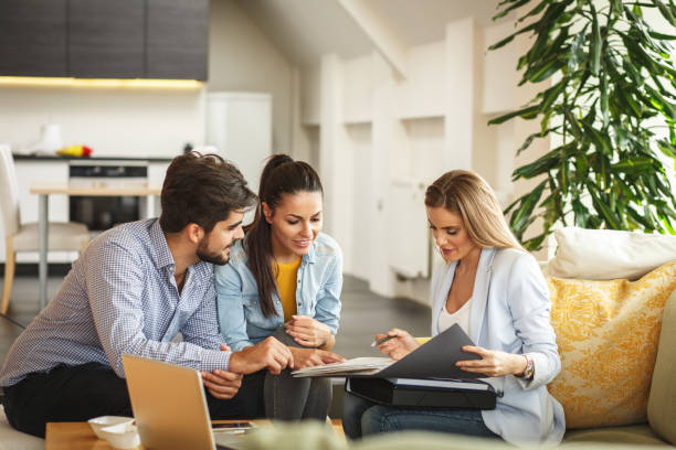 Three people are sitting on a sofa, looking at a document together.